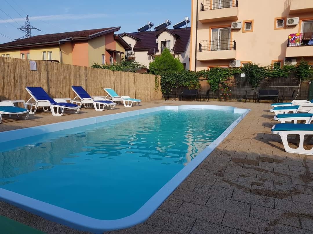 Piscină exterioară cu șezlonguri albastre la Vila OK Costinești