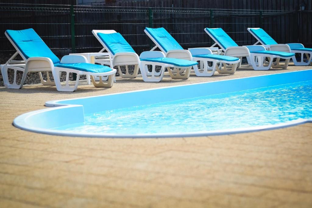 Detaliu cu șezlonguri și piscină în lumina dimineții