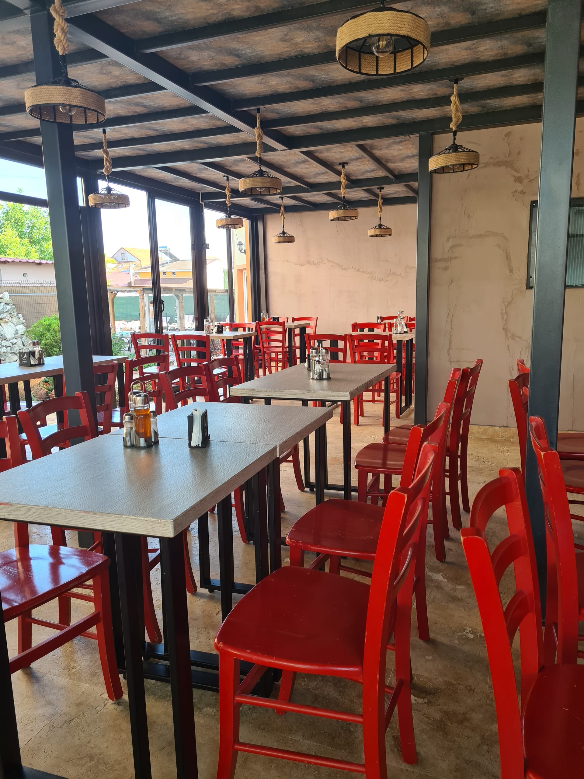 Terasa restaurantului propriu al Vilei OK, cu scaune roșii și lumini calde
