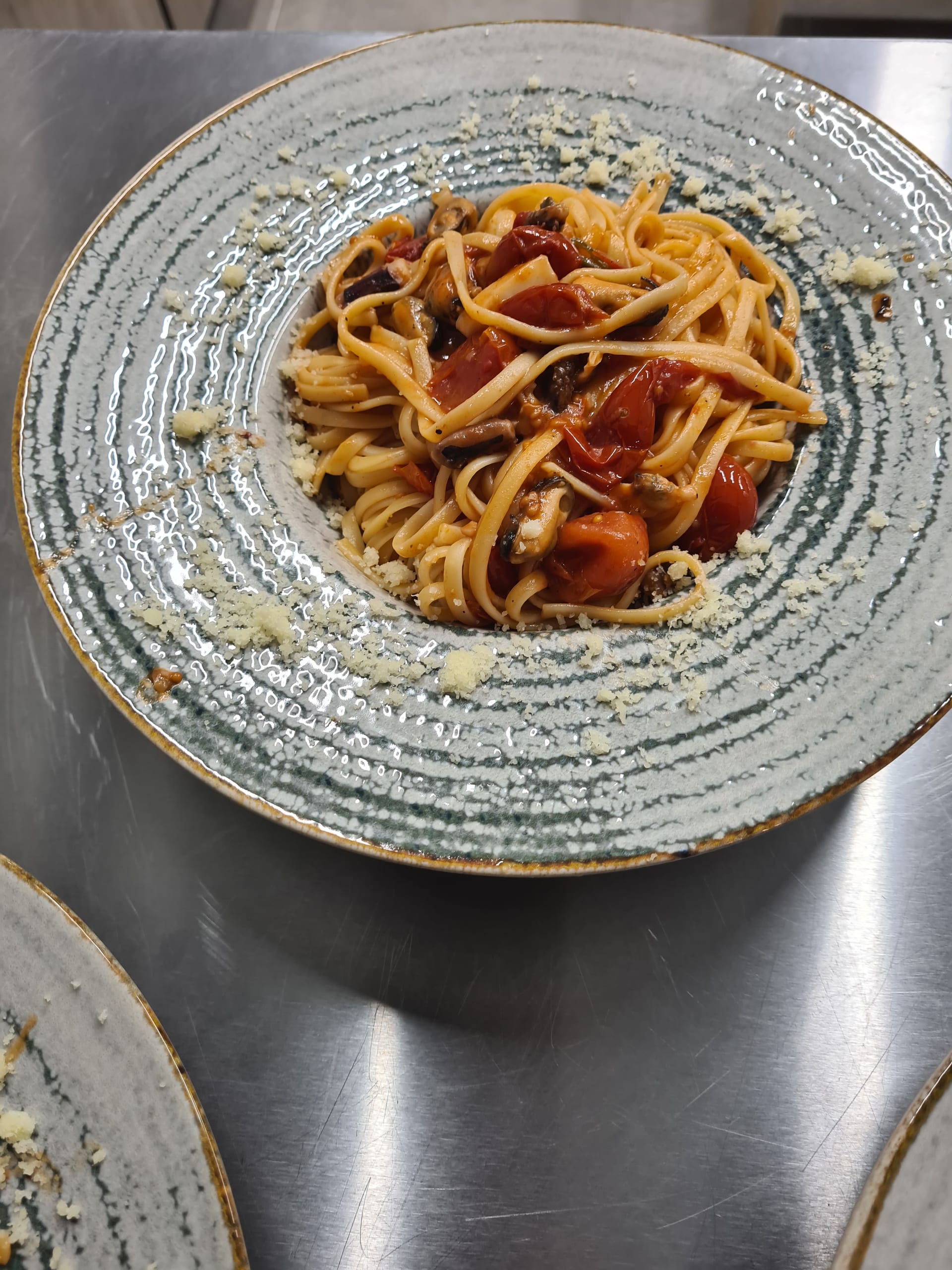 Preparat cu paste, roșii cherry și fructe de mare, servit la restaurant