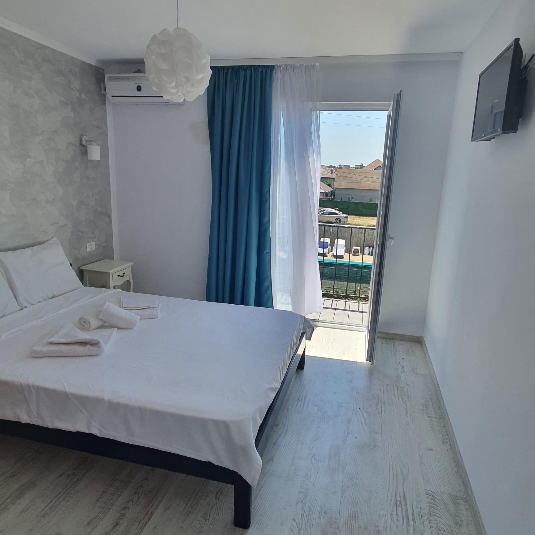 Cameră dublă modernă, cu draperii turcoaz și balcon cu vedere spre piscină